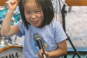 Backbeat Music Academy, Portland OR, a girl sings into a microphone during a class at a rock band summer camp