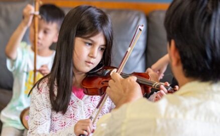 Backbeat Music Academy - girl playing the violin while her teacher assists at backbeat Music