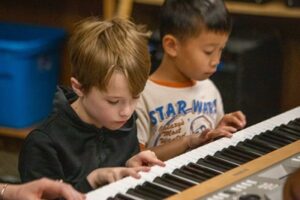 Backbeat Music Academy - two boys playing the piano together at a rock band summer camp